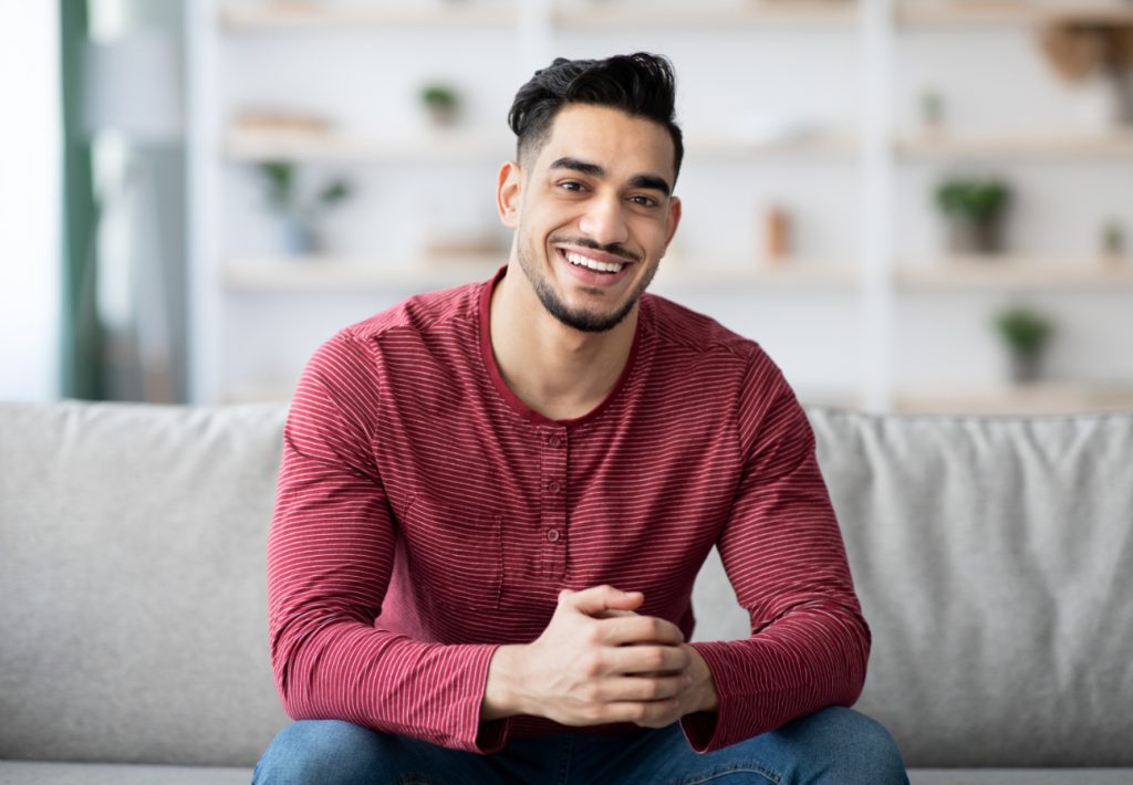 handsome arab guy chilling at home smiling at came 8LL5E7Y 1